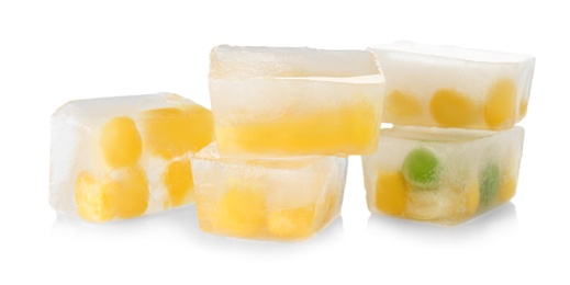 Photo of Corn grains and green peas in ice cubes on white background. Frozen vegetables