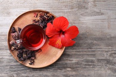 Photo of Delicious hibiscus tea and flowers on wooden table, top view. Space for text
