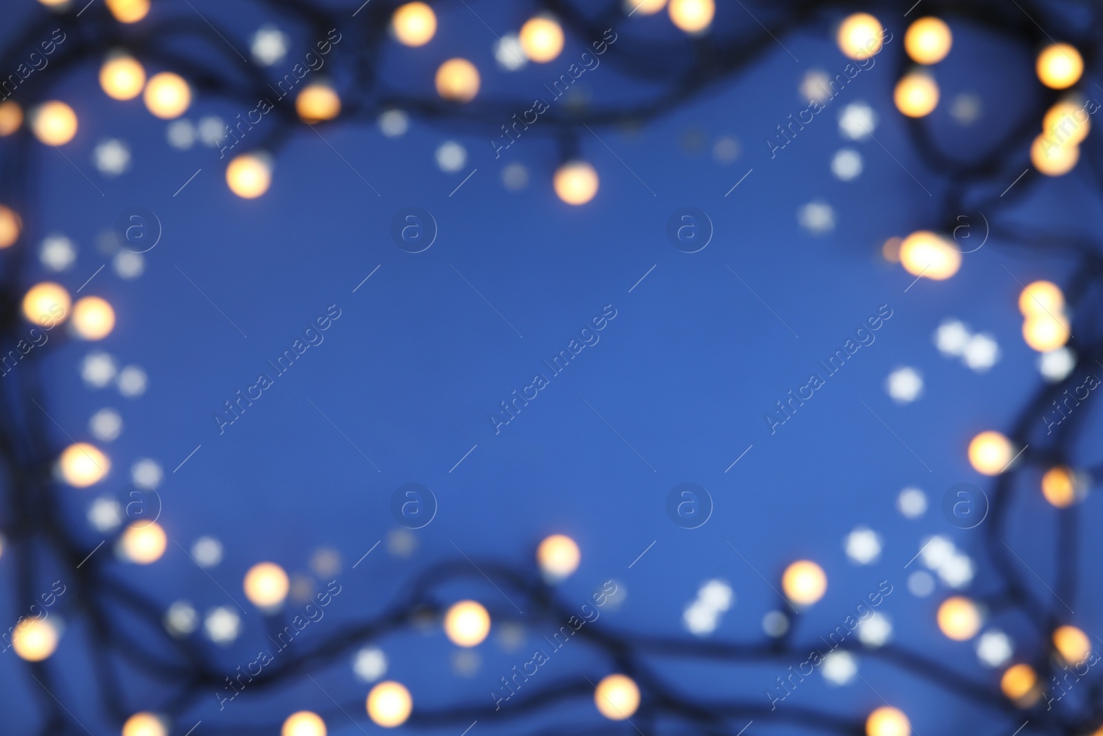 Photo of Blurred view of glowing Christmas lights on color background, top view