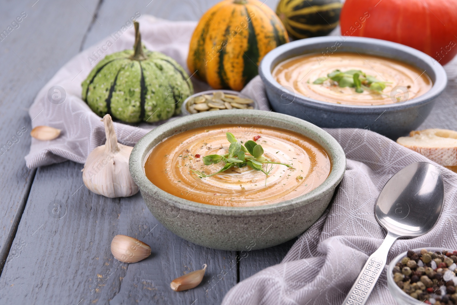 Photo of Delicious pumpkin soup served on gray wooden table