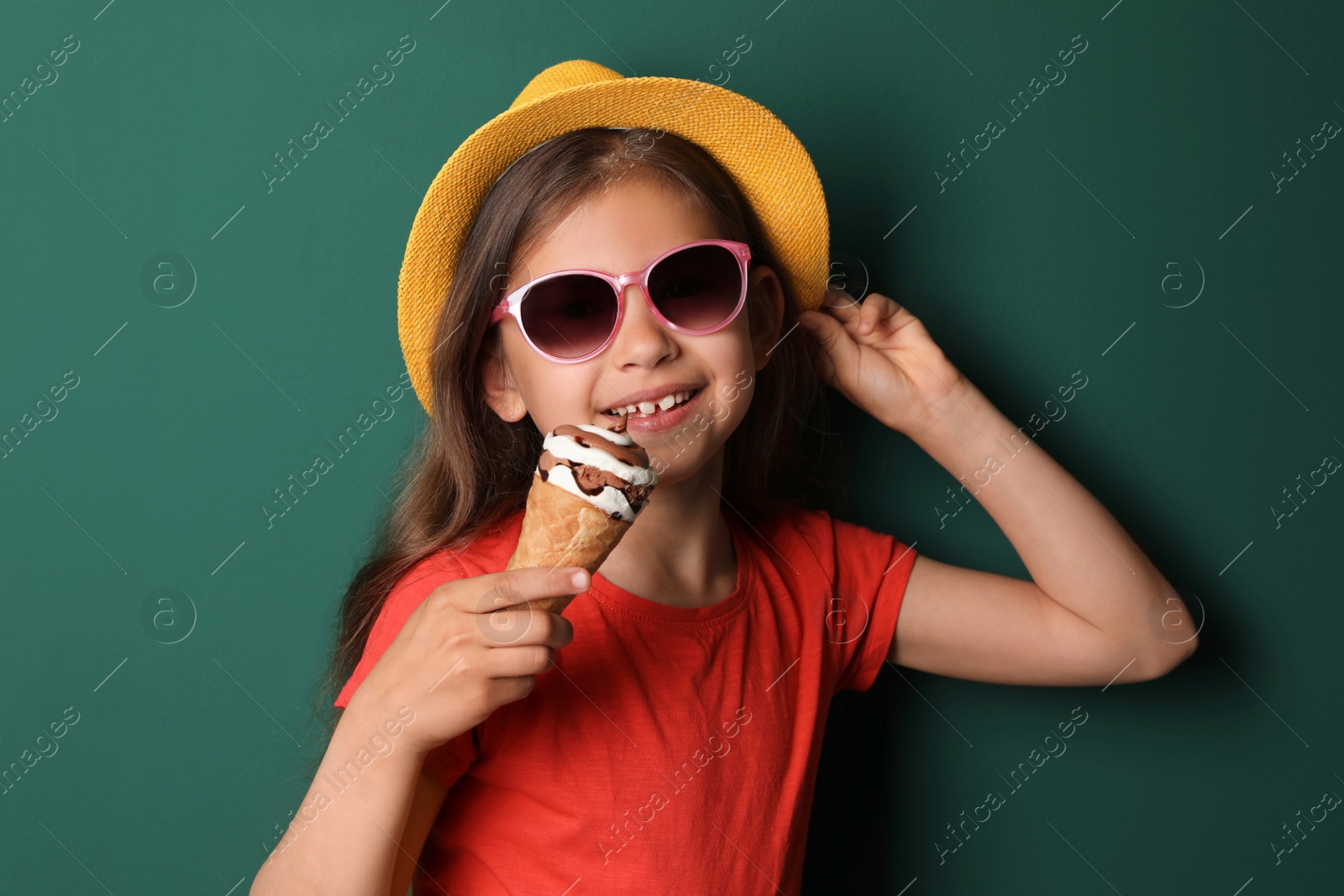 Photo of Cute little girl with delicious ice cream against color background