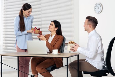 Photo of Colleagues presenting gifts to woman in office