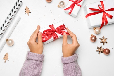 Young woman holding Christmas gift on white background, flat lay