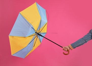 Photo of Man with umbrella caught in gust of wind on pink background, closeup