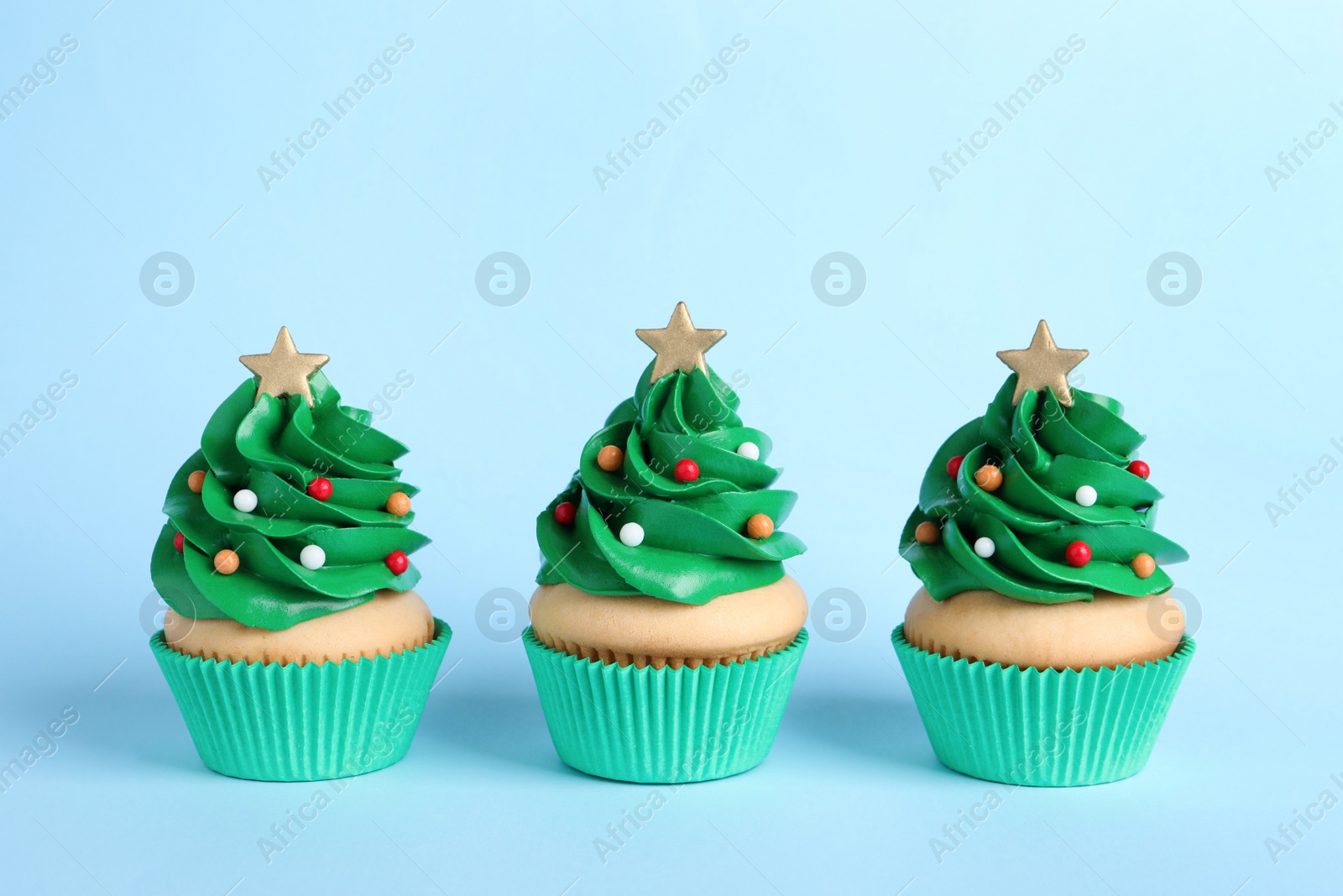 Photo of Christmas tree shaped cupcakes on light blue background