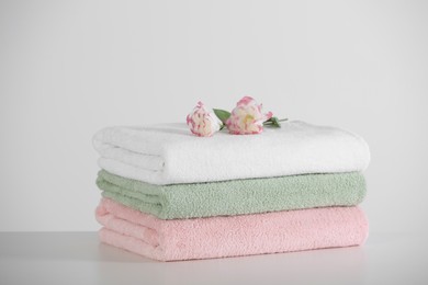 Soft folded towels with eustoma flowers on white table