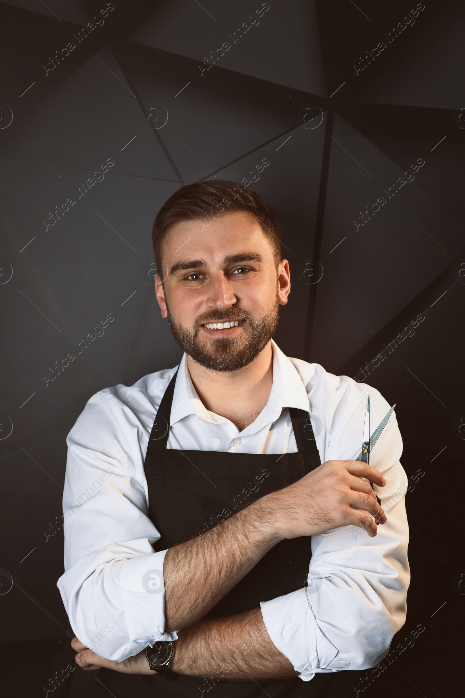 Photo of Happy hairdresser with professional scissors on dark background