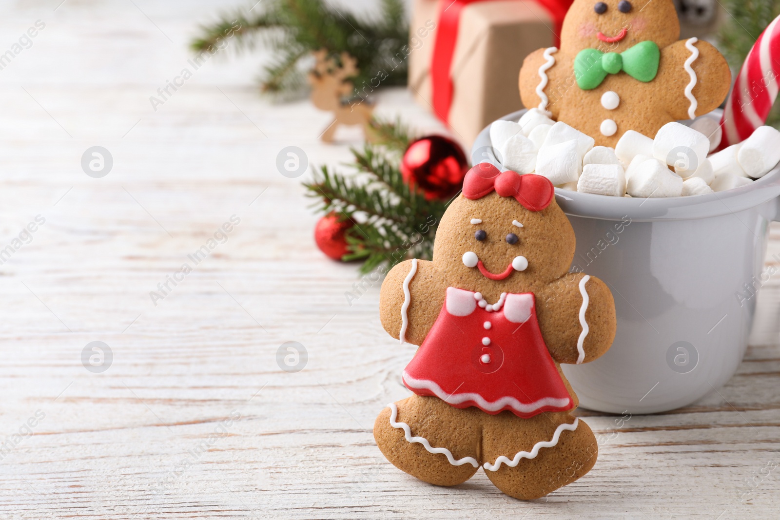 Photo of Decorated gingerbread cookies on white wooden table, space for text