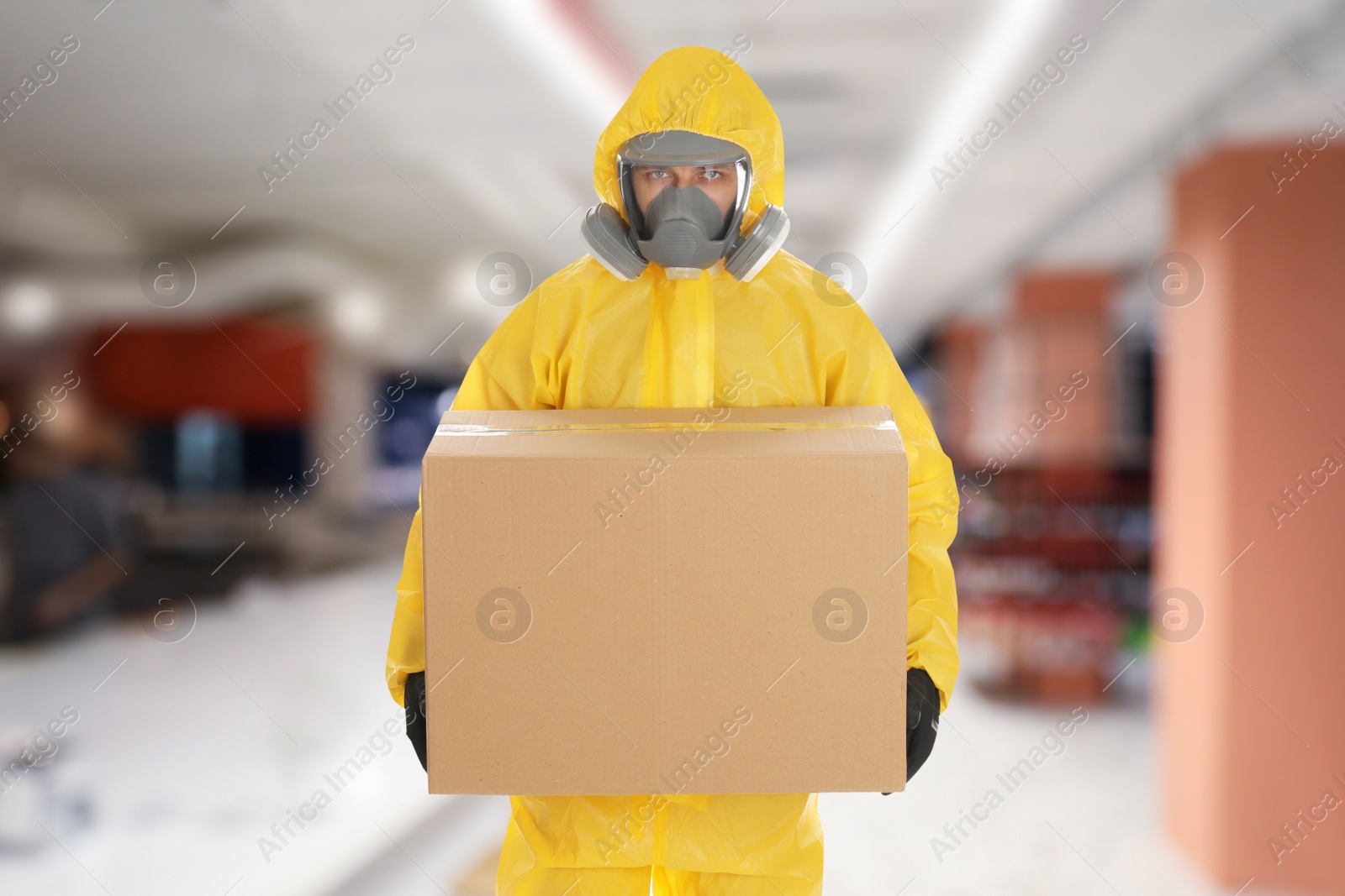 Image of Man wearing chemical protective suit with cardboard box in store. Wholesale market
