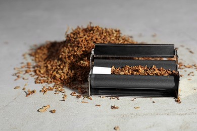 Photo of Roller with filter and tobacco on light grey table. Making hand rolled cigarette
