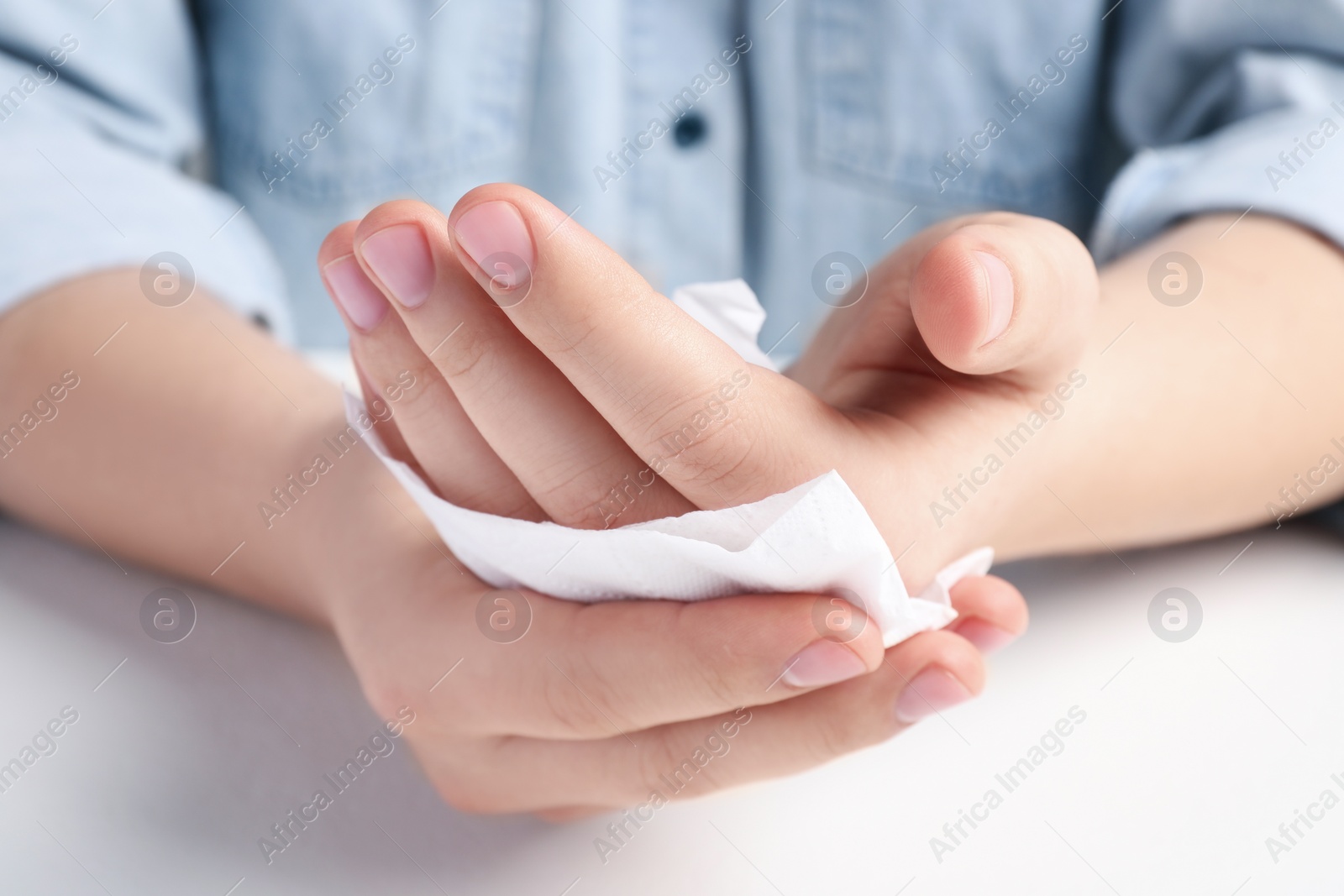 Photo of Man wiping hands with paper towel at white table, closeup