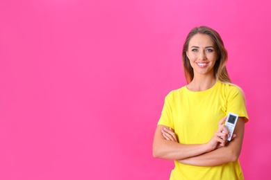 Photo of Young woman with air conditioner remote on hot pink background. Space for text