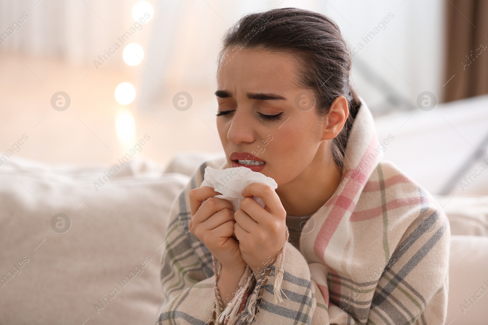 Photo of Young woman suffering from runny nose in living room