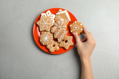 Photo of Woman taking tasty homemade Christmas cookie from plate on table, top view