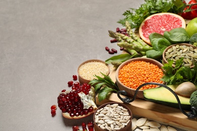 Photo of Fresh vegetables, fruits and seeds on grey table, space for text