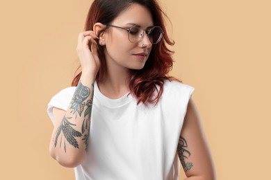 Portrait of beautiful tattooed woman on beige background