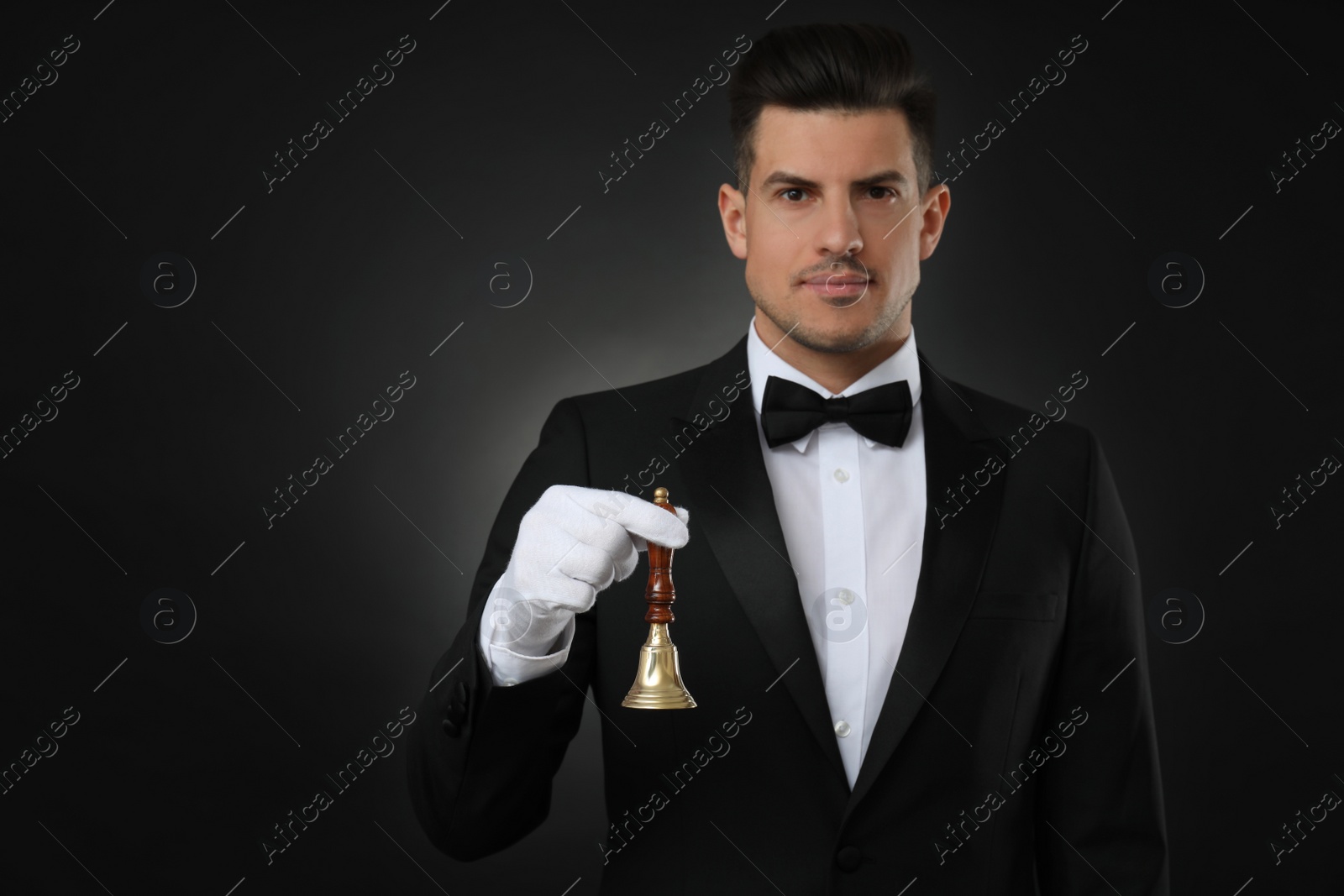Photo of Butler holding hand bell on black background, space for text