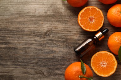 Flat lay composition with tangerine essential oil on wooden table, space for text