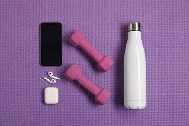 Photo of Flat lay composition with stylish thermo bottle and dumbbells on purple textured background