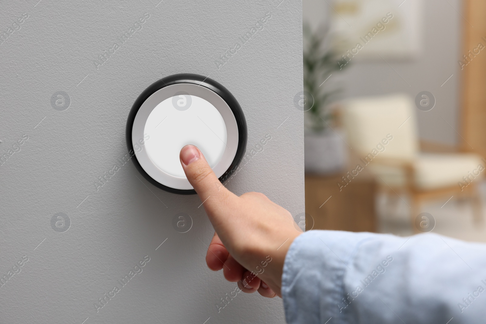 Photo of Woman adjusting thermostat on white wall indoors, closeup. Smart home system