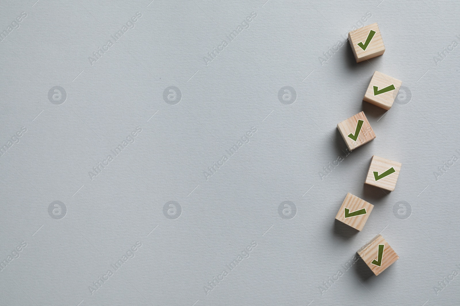 Image of Wooden cubes with check marks on light grey background, flat lay. Space for text