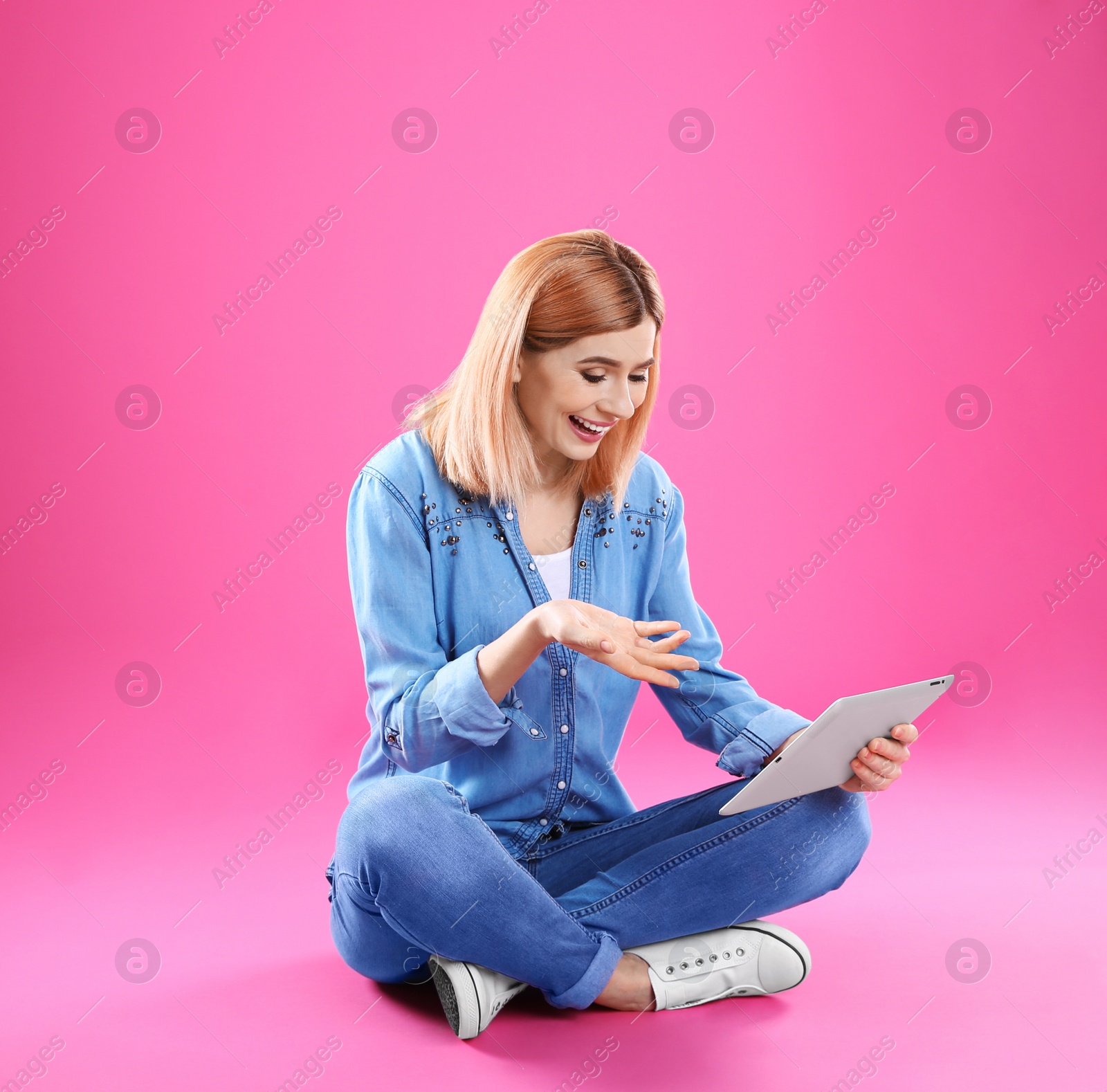 Photo of Woman using tablet for video chat on color background