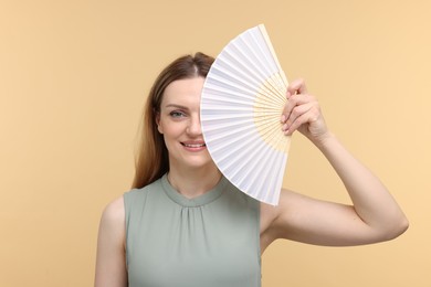 Photo of Happy woman with hand fan on beige background