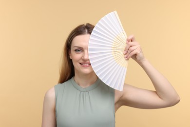 Happy woman with hand fan on beige background