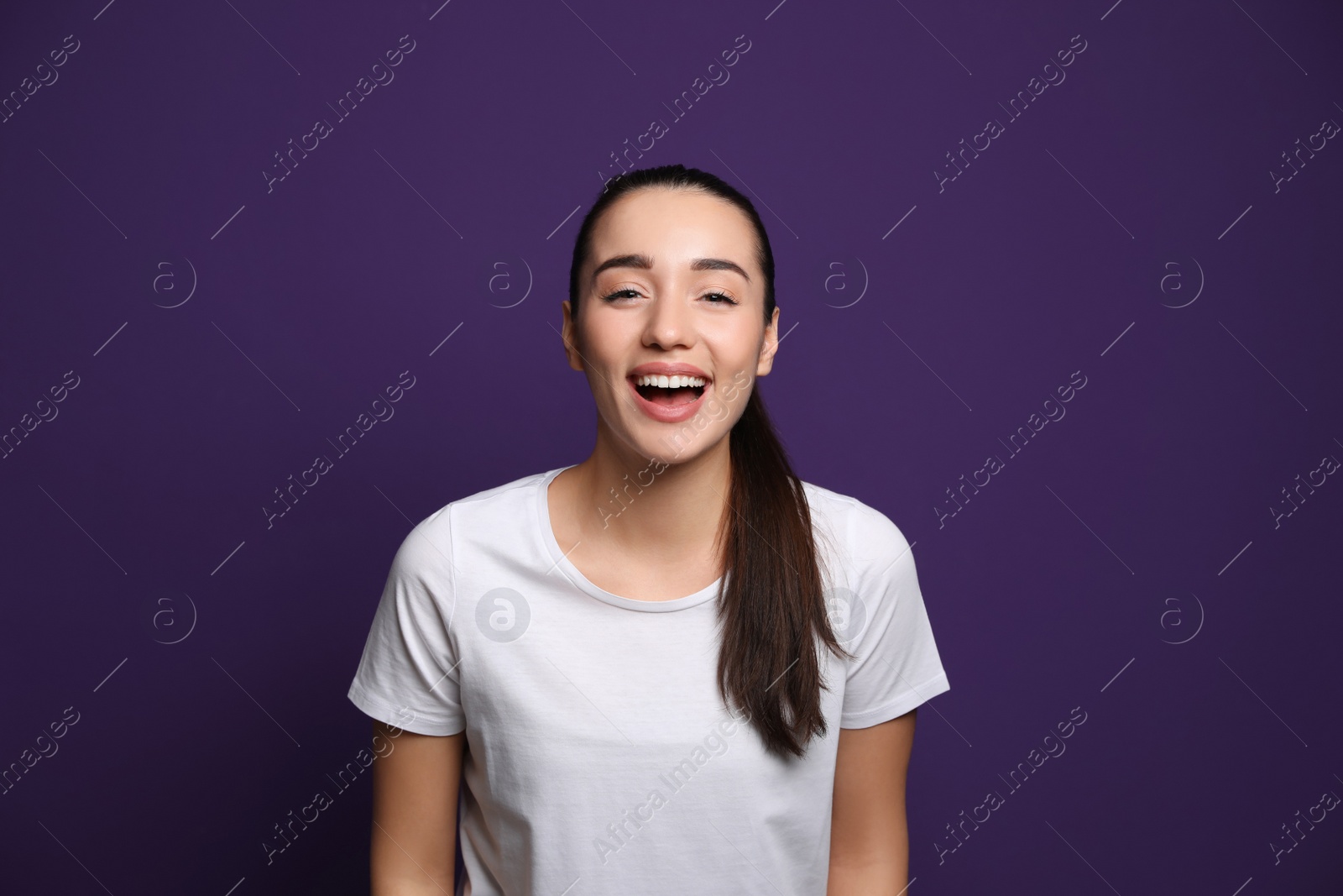 Photo of Beautiful young woman laughing on purple background. Funny joke