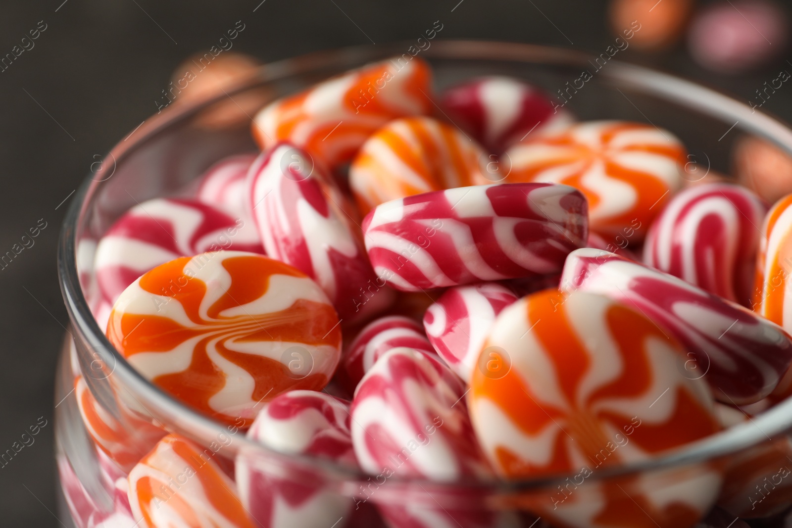 Photo of Colorful hard candies in glass jar on table, closeup