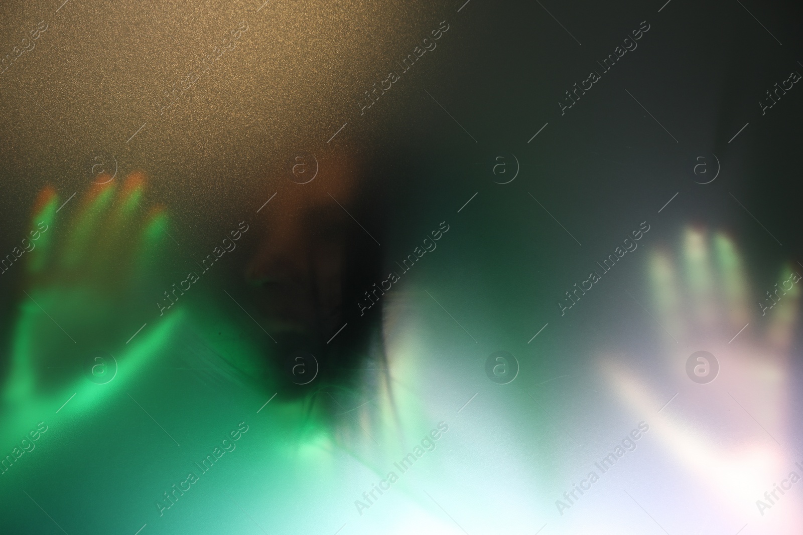 Photo of Silhouette of creepy ghost behind glass against color background