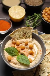Delicious creamy hummus with chips and different ingredients on table, closeup