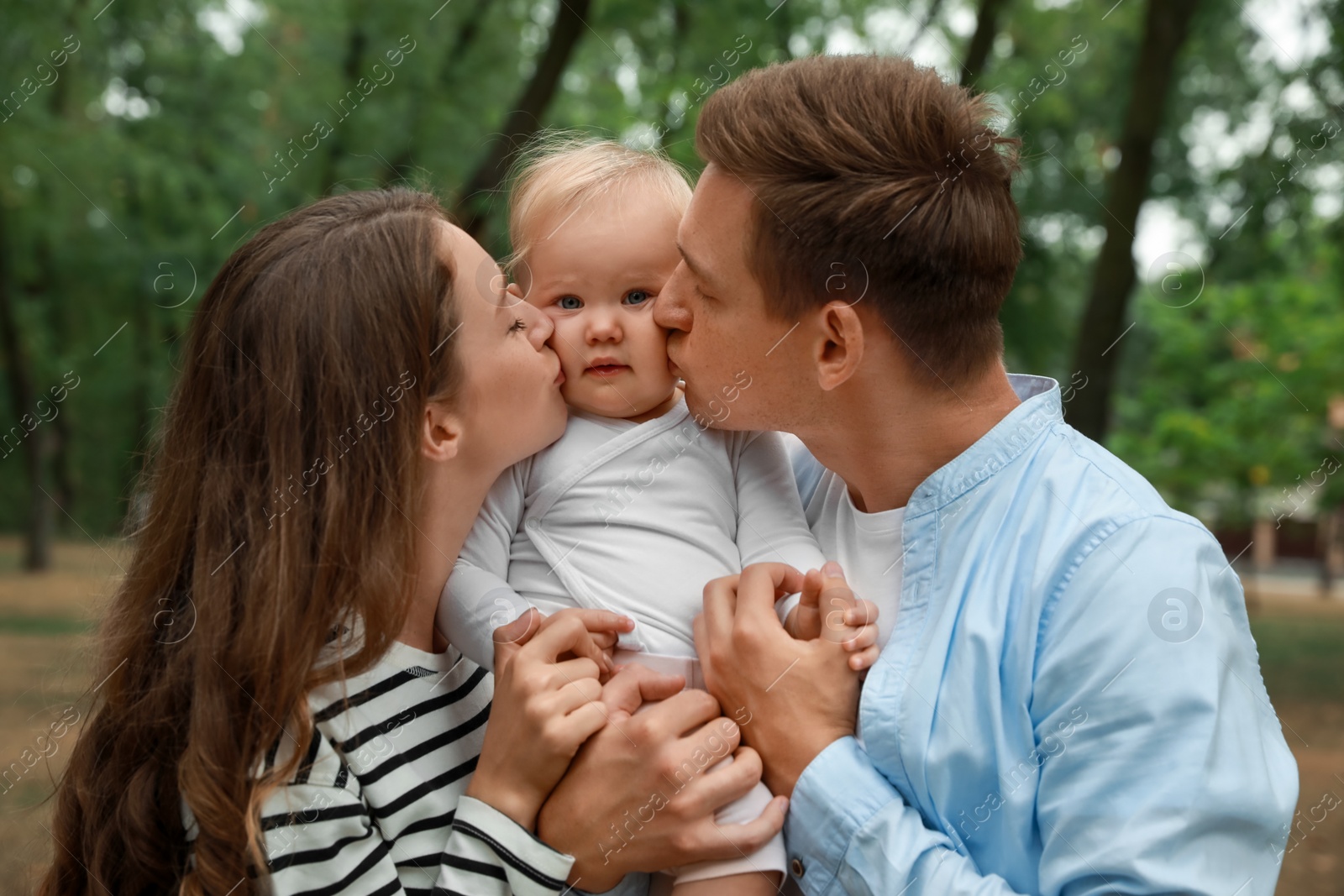 Photo of Parents with their cute baby spending time together outdoors. Happy family