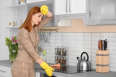 Tired housewife cleaning kitchen at home