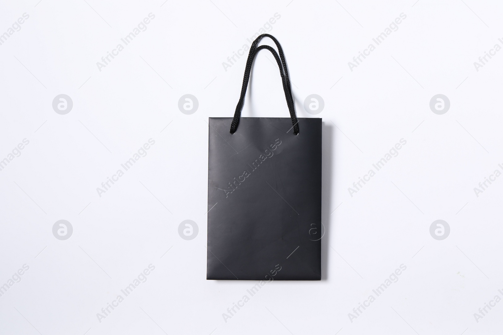 Photo of One black paper shopping bag on white background, top view