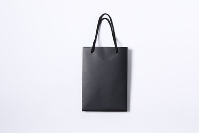 One black paper shopping bag on white background, top view