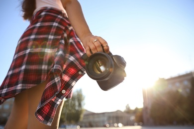 Photo of Young photographer with professional camera outdoors, closeup. Space for text