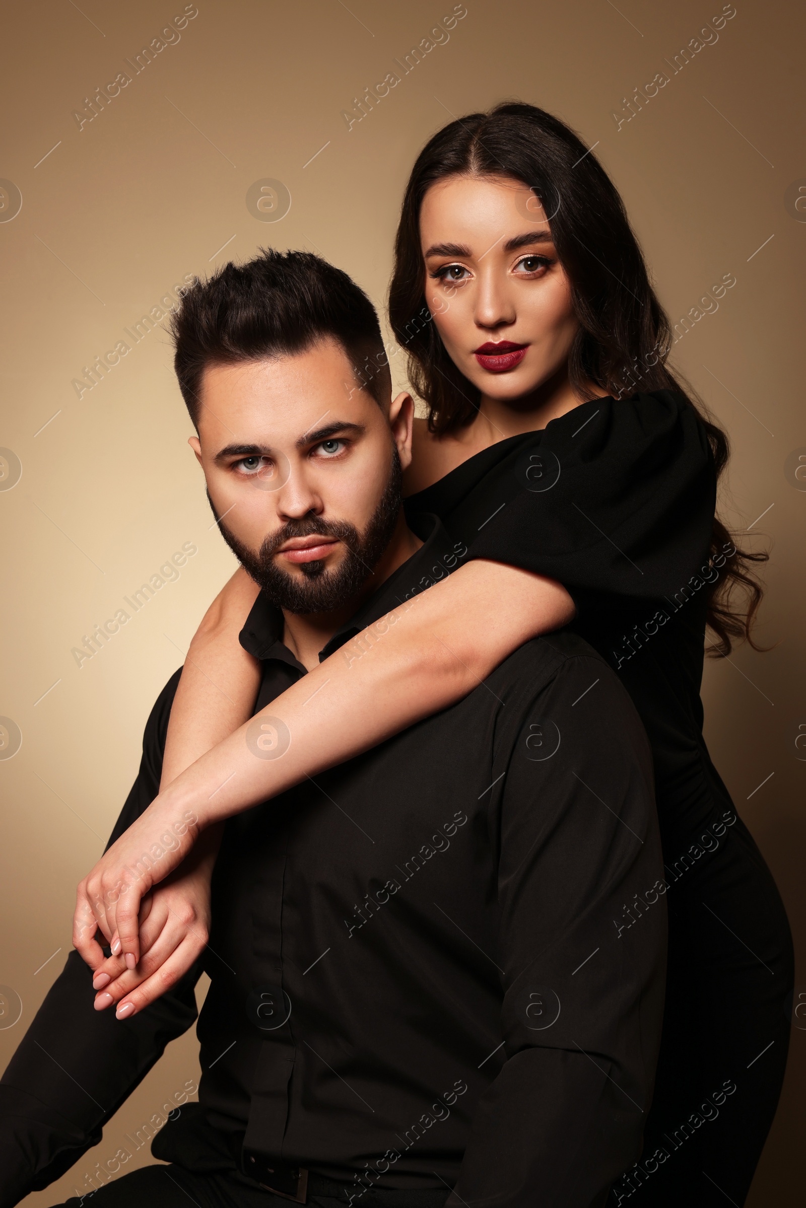 Photo of Handsome bearded man with sexy lady on light brown background