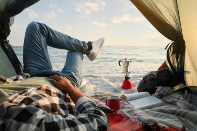 Photo of Man resting in camping tent near sea, closeup