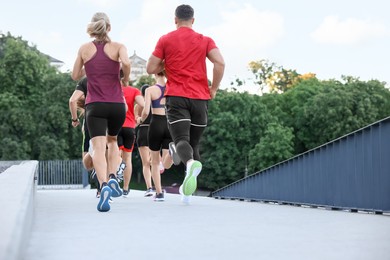 Photo of Group of people running outdoors, back view