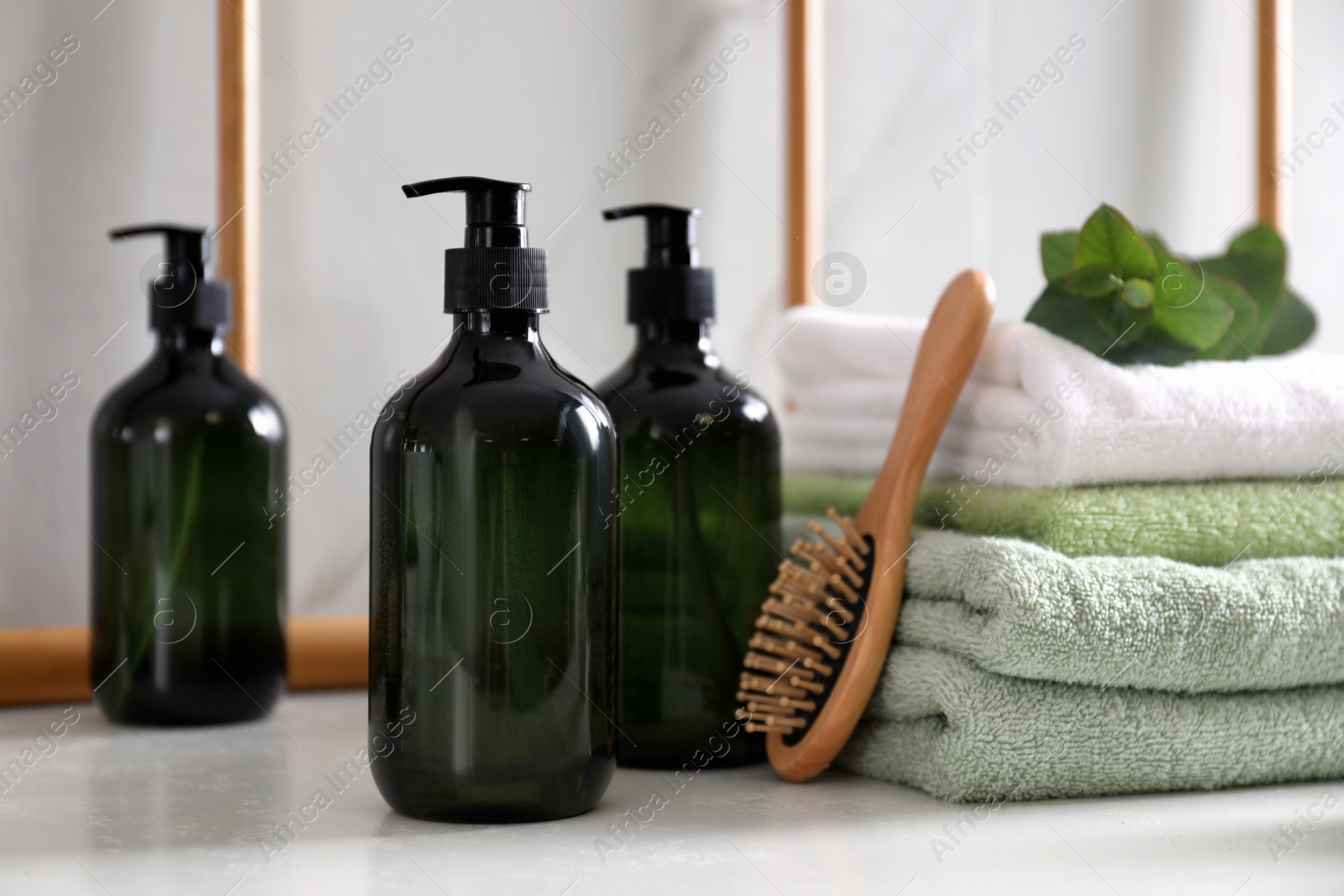 Photo of Soap dispensers, brush and towels on countertop in bathroom