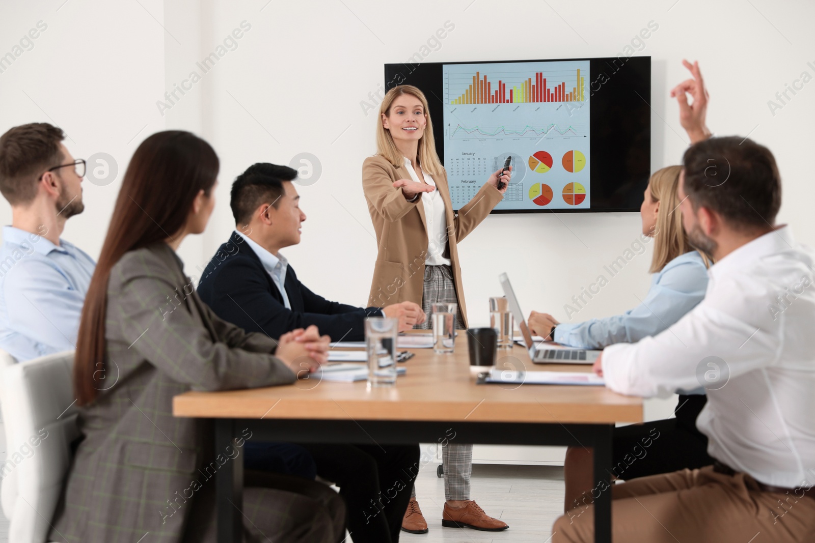 Photo of Businesswoman showing charts on tv screen in office