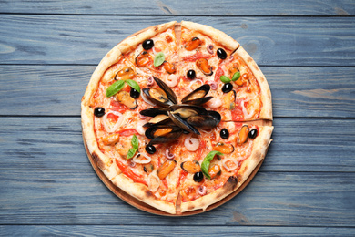 Tasty pizza with seafood and fresh basil on blue wooden table, top view