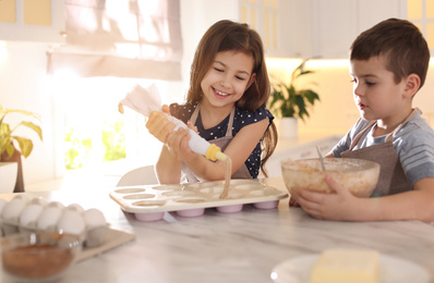 Photo of Cute little children cooking pastry in kitchen at home