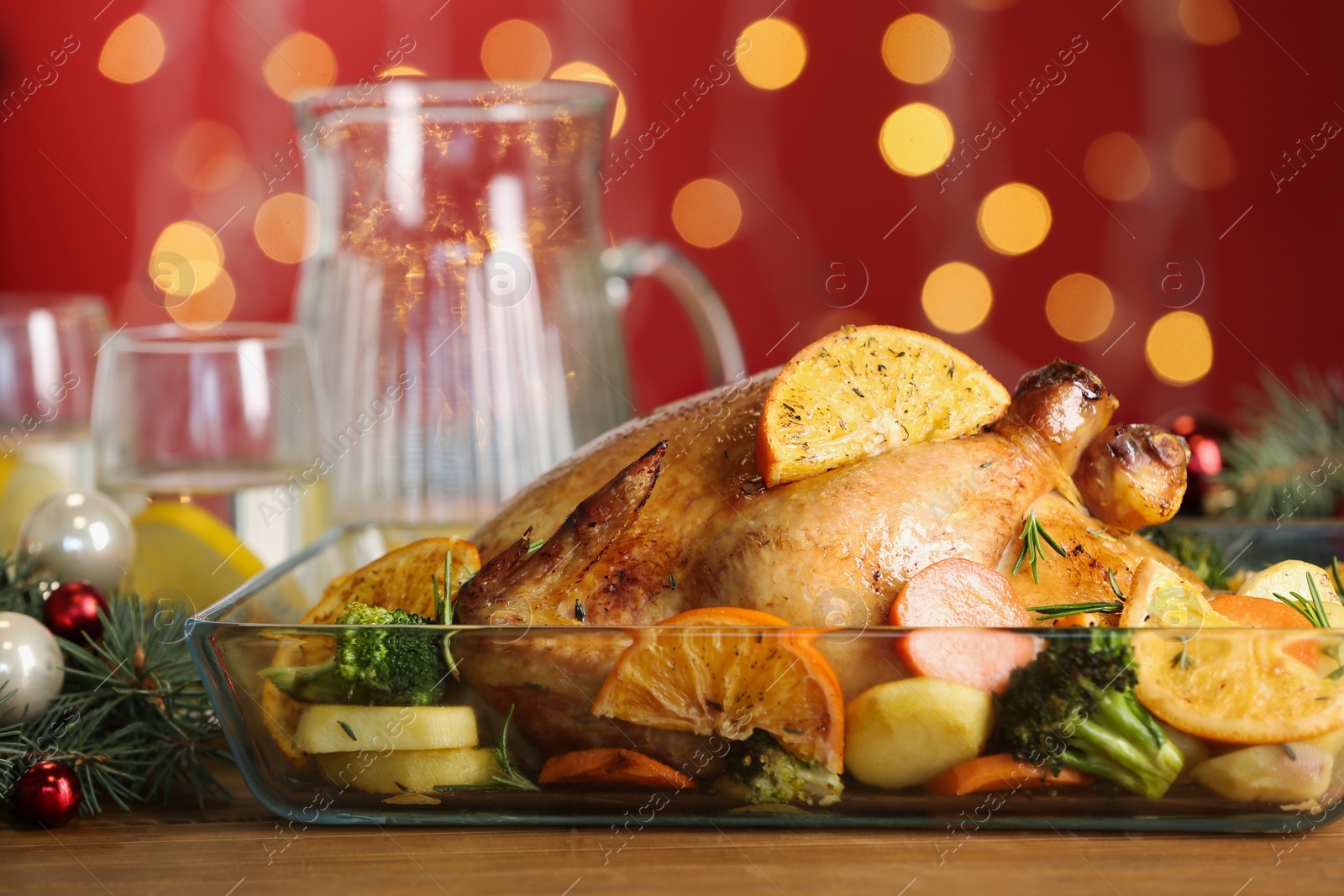 Photo of Delicious chicken with oranges and vegetables on table against blurred festive lights, closeup