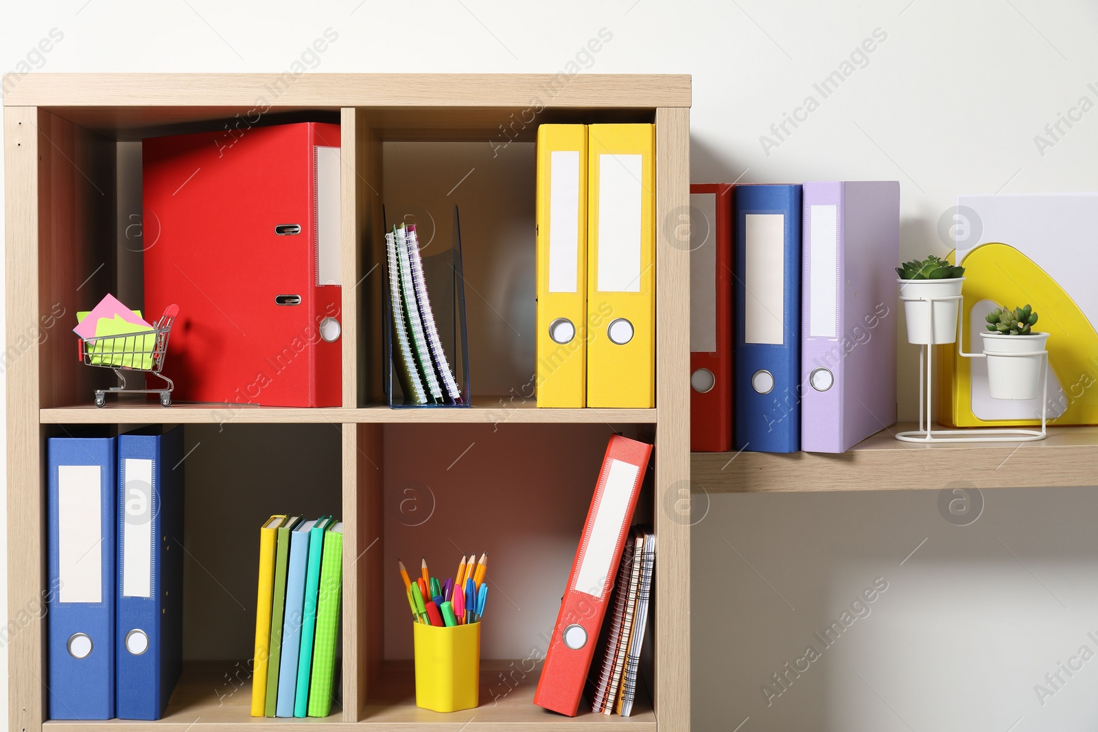 Photo of Colorful binder office folders and other stationery on shelving unit indoors