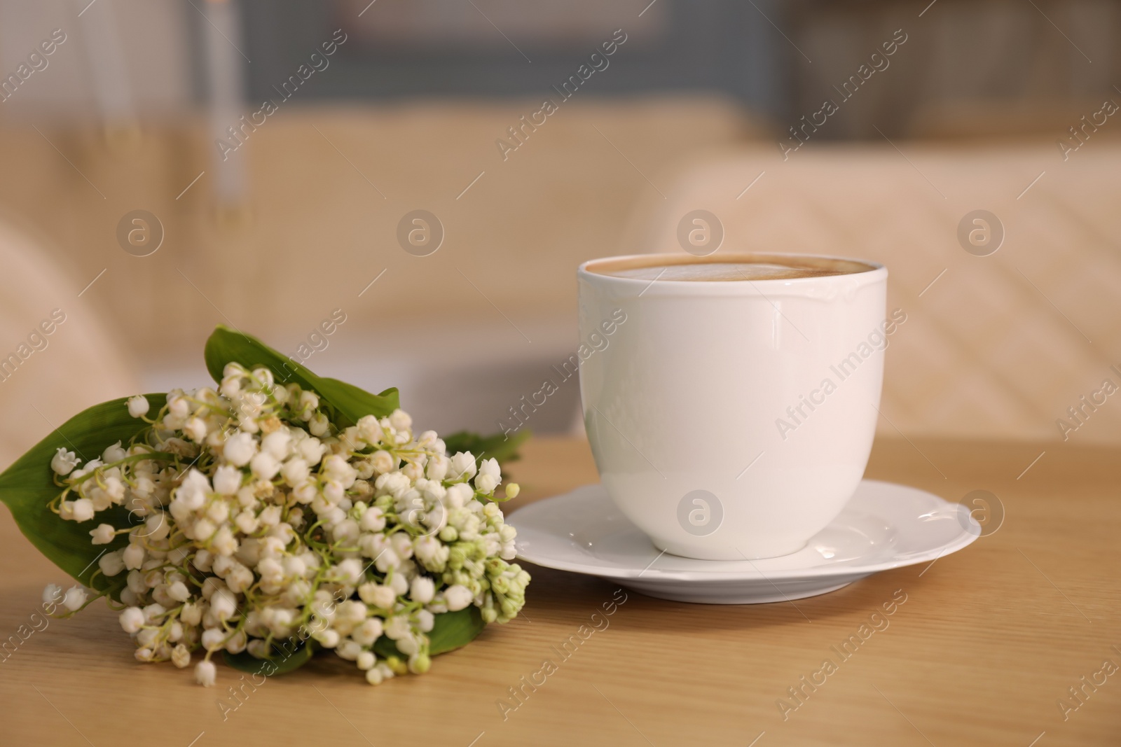 Photo of Cup of aromatic morning coffee and flowers on wooden table in cafe