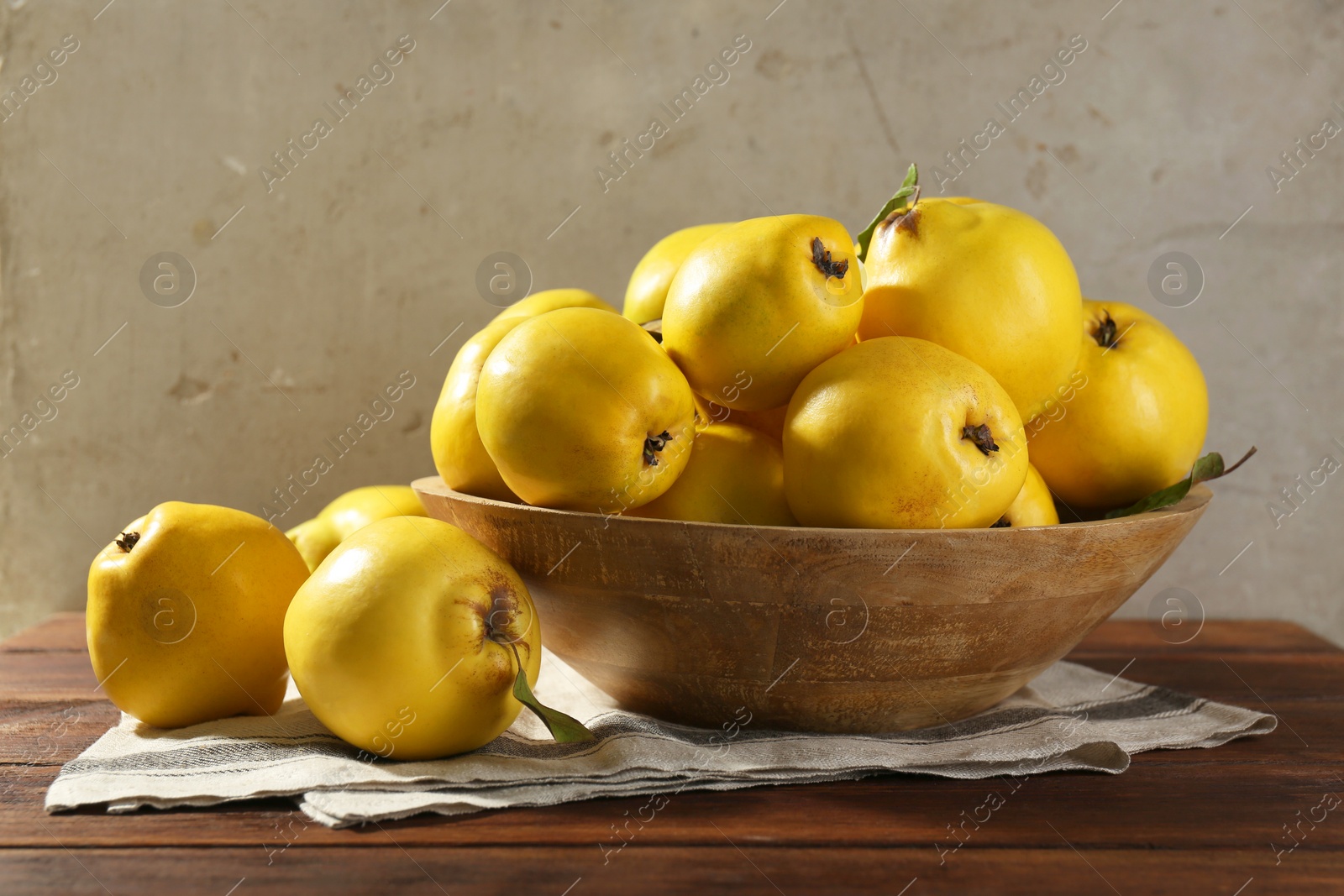 Photo of Tasty ripe quince fruits in bowl on wooden table