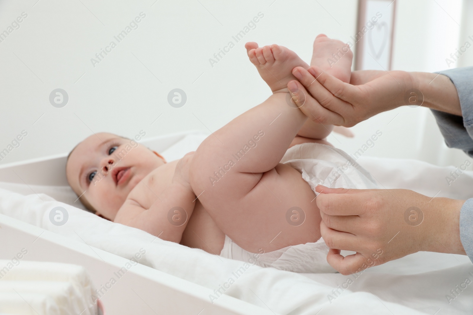 Photo of Mother changing baby's diaper at home, focus on hands