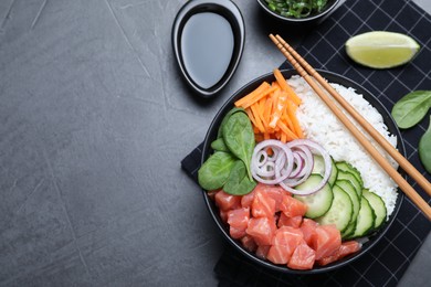 Photo of Delicious poke bowl with salmon and vegetables served on grey table, flat lay. Space for text